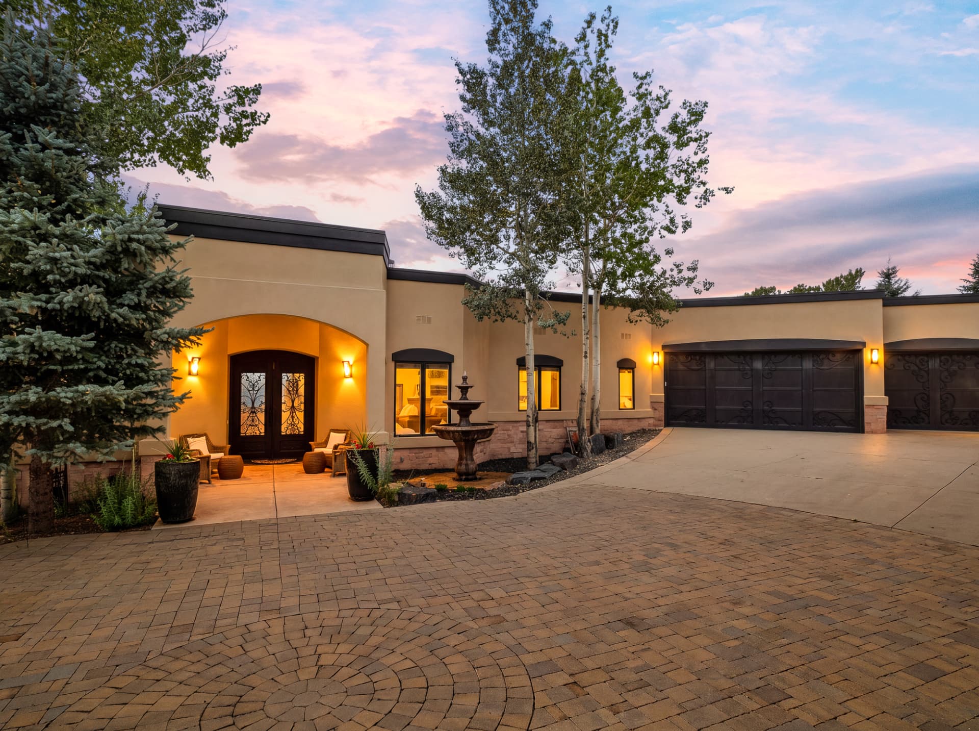 Front entry at dusk with warm lighting and fountain